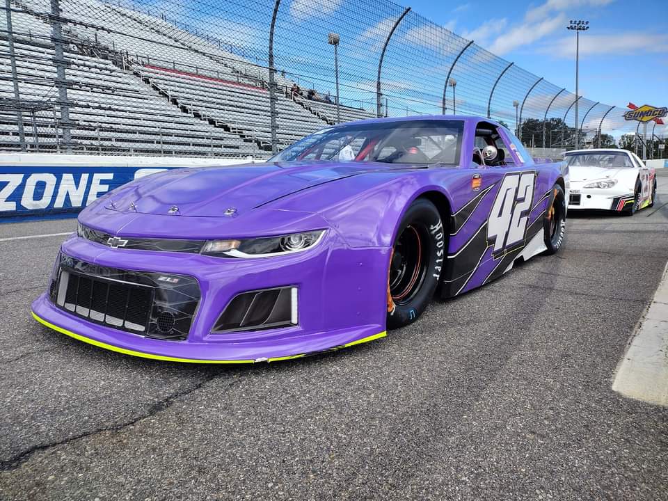 The purple #42 Chevrolet on pit road before a daytime race