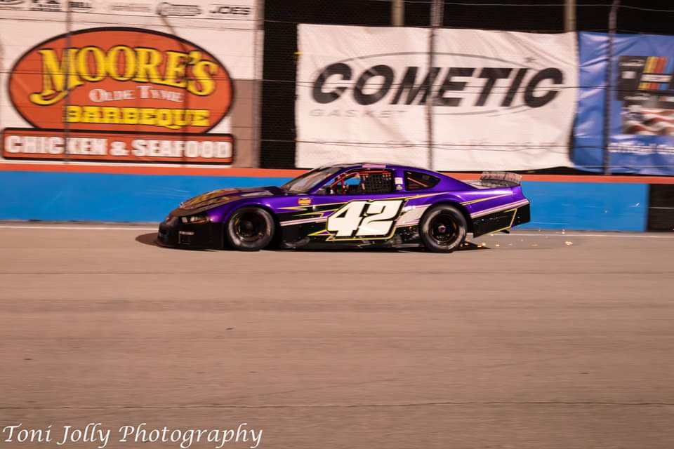 The purple #42 at speed past trackside sponsor banners