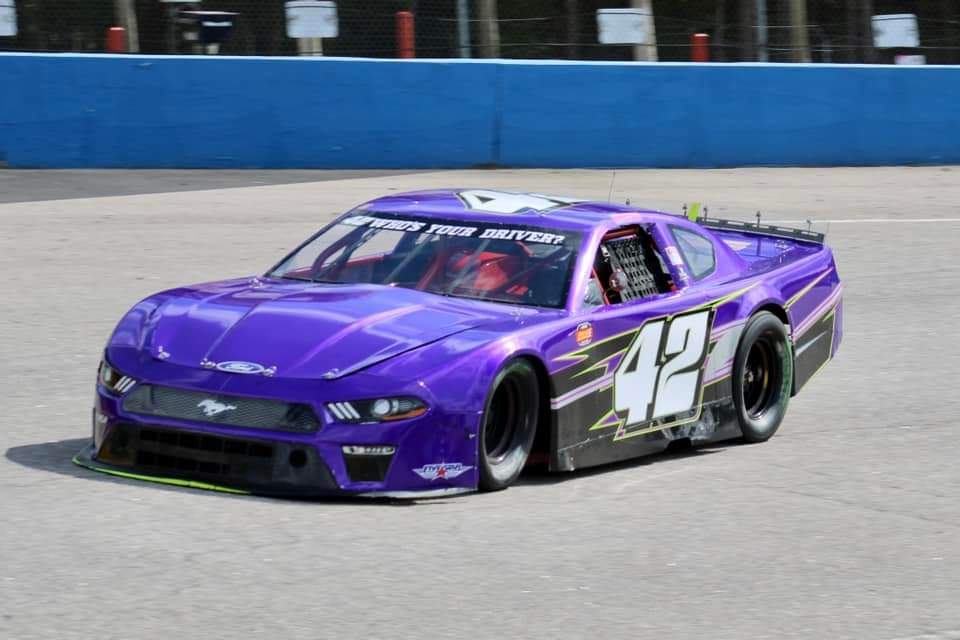 The purple #42 Ford Mustang on track during a daytime session