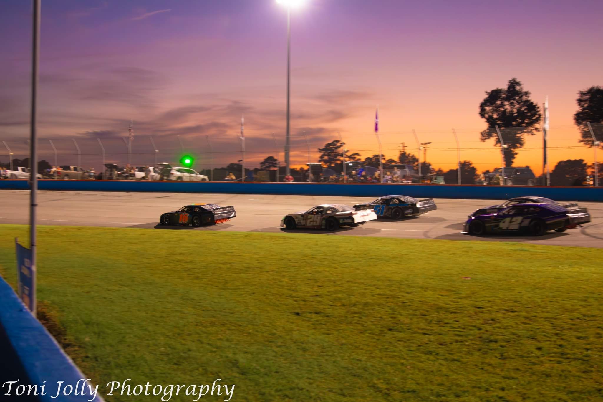 The #42 running in a pack at twilight as the sun sets over the track