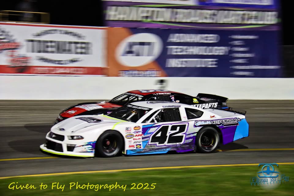 The #42 racing at night past trackside sponsor banners